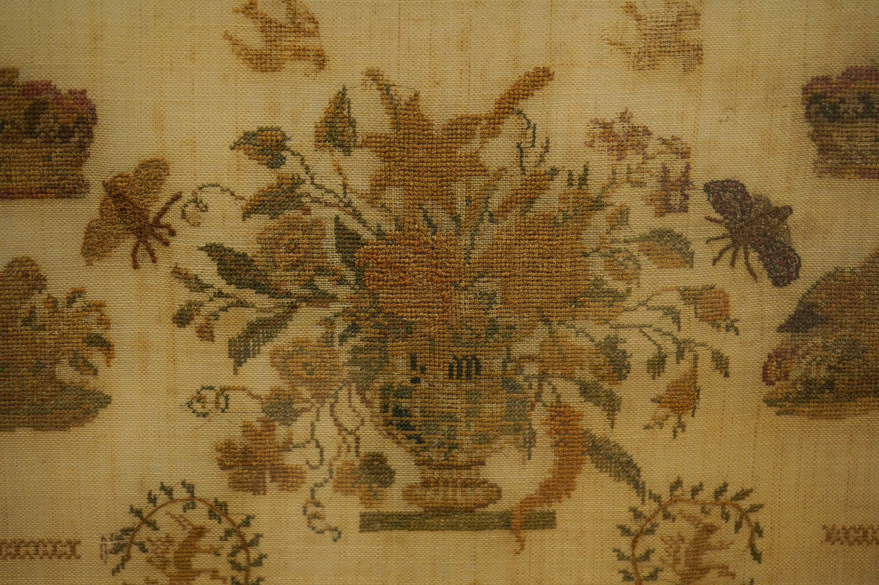 A rosewood framed sampler, dated 1842, by Martha Brook, aged 11years, worked above with large motifs of flower baskets and a bird, a vase of flowers beneath, surrounded by crowns, butterflies and chicks above two small c